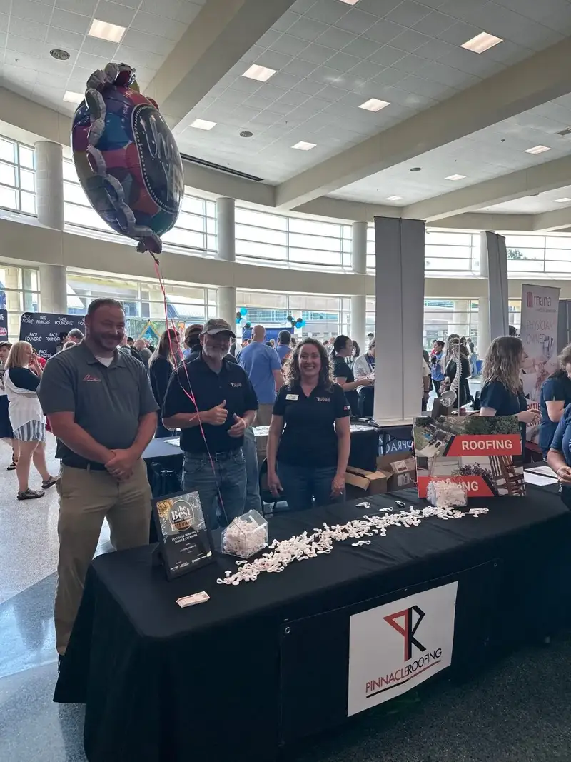 Pinnacle Roofing team at a Northwest Arkansas community expo, displaying their Best of NWA award at their branded booth