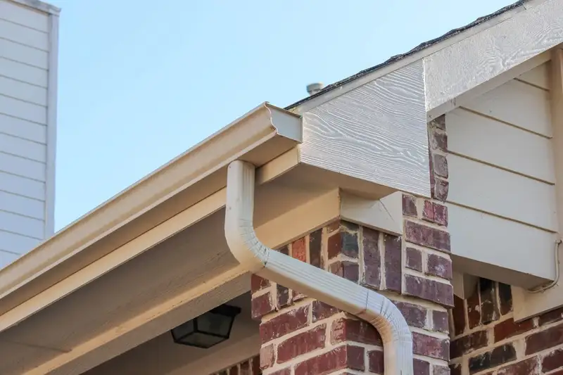 Seamless gutter replacement in Fayetteville, Arkansas — aluminum gutter and downspout install on a brick home